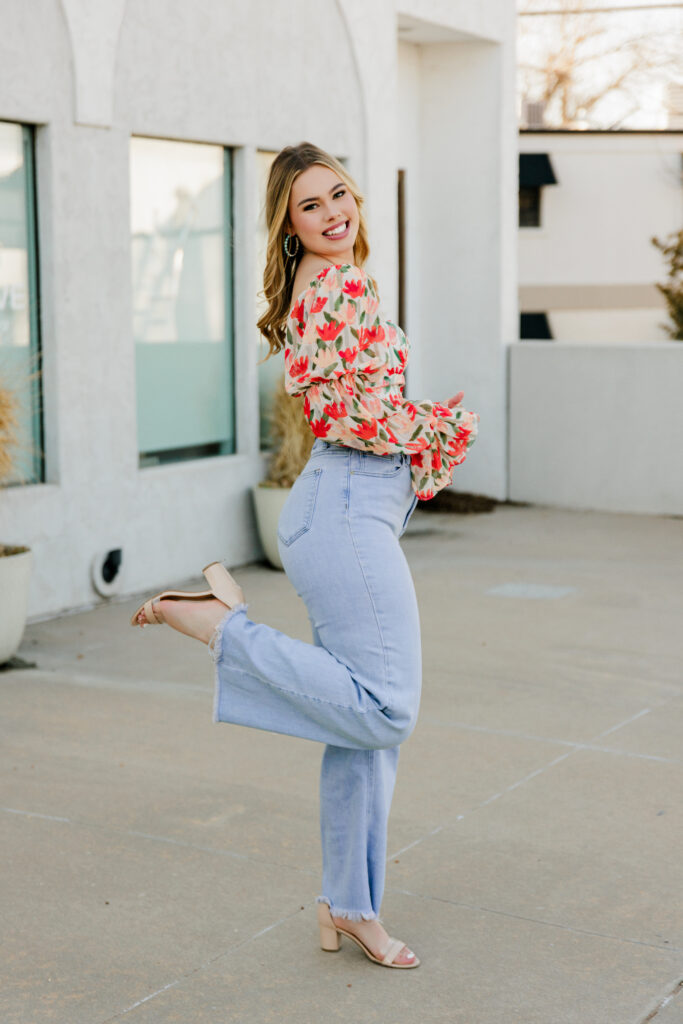 senior photo outfits. senior posing with floral top, jeans, and chunky heels