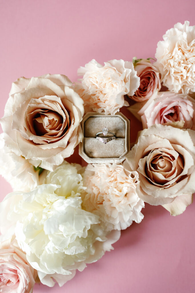 Bridal flat lay with wedding invitation, blush florals, jewelry, and heels at Rose Briar Place