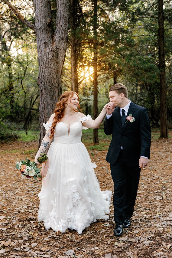 a bride and groom walking through the woods in a dress found at a wedding consignment dress okc shop