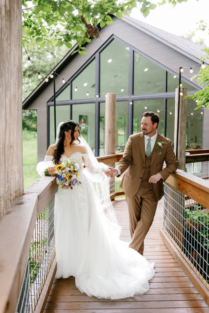 Beautiful bride and groom gazing at each other on a modern bridge